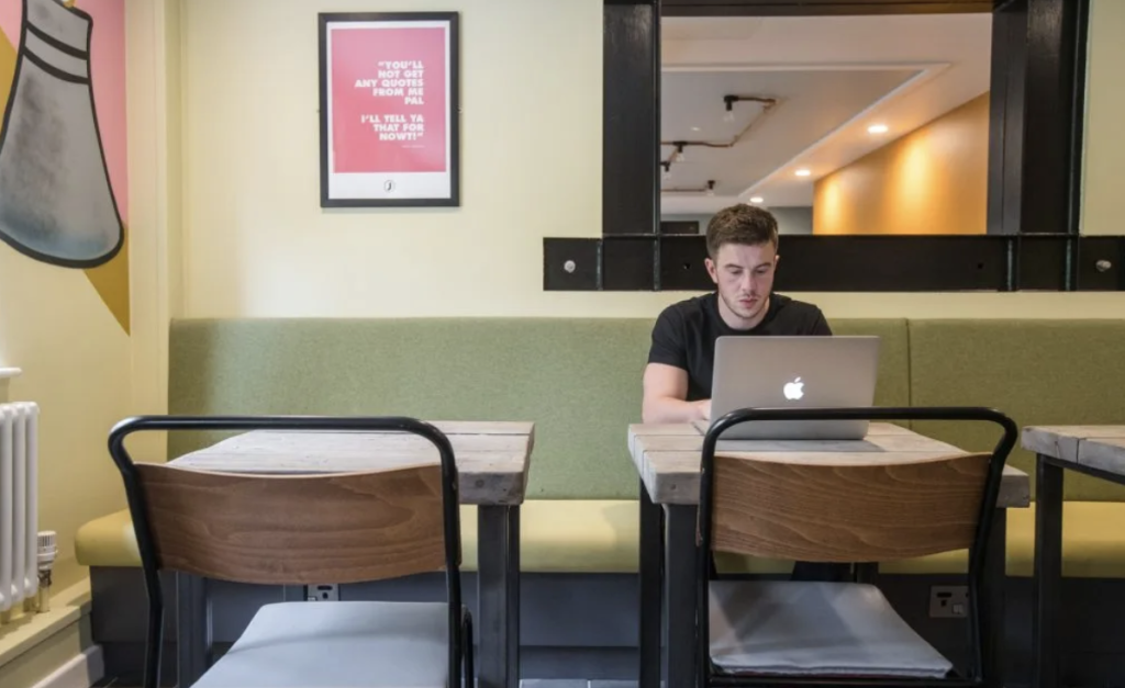 Guest at Jonas long-stay hotel in Sheffield working on his laptop sat at a table in a communal area